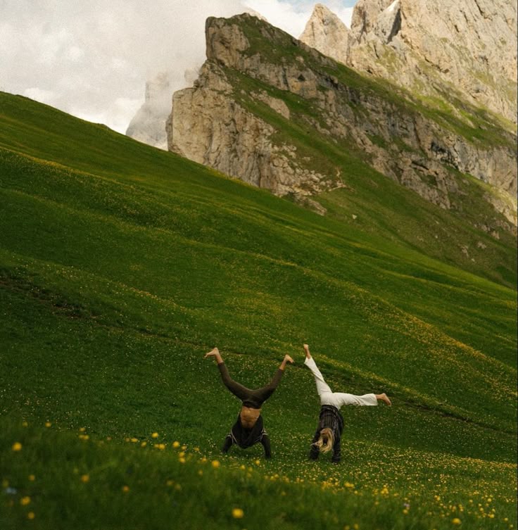 two humans cartwheeling down a mountain full of greenery.